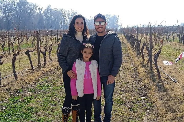 Family of three standing among bare winter vines at Cousiño Macul