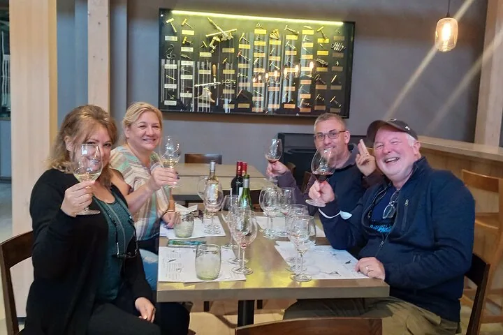 Four guests raising red and white wine in a modern tasting room
