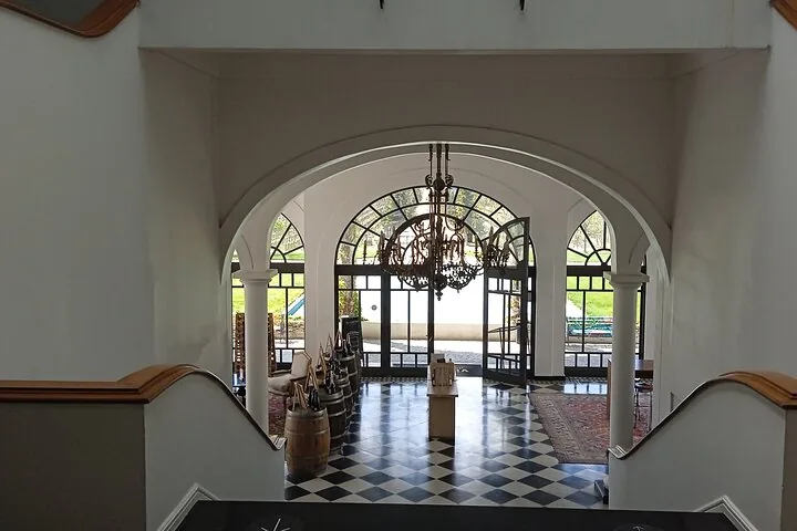 Arched hall with a chandelier, checkered floor and barrels by the doors