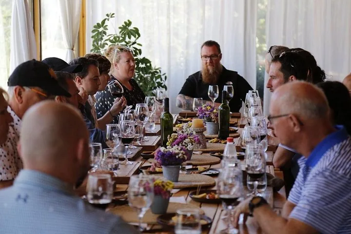 Guests seated at a long lunch table set with wine and flower vases
