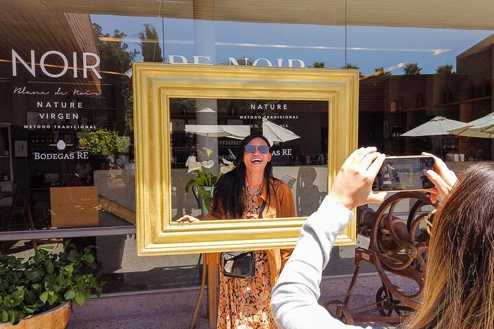 Laughing visitor framed by a gilt picture frame outside the Bodegas RE shop
