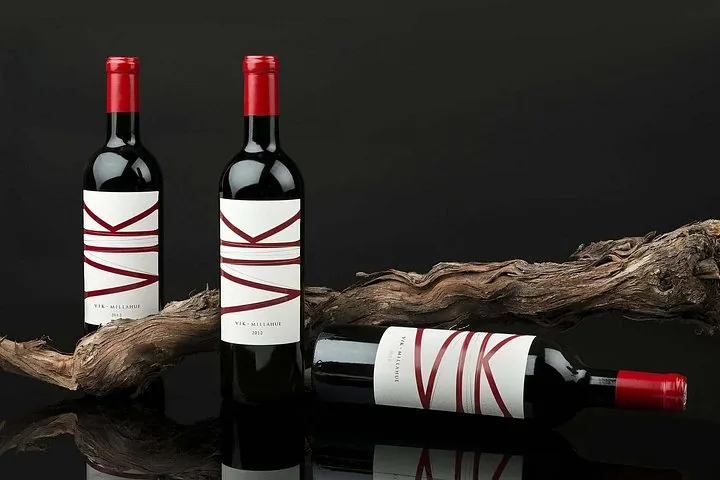 Three bottles of VIK Millahue red wine displayed with an old vine trunk
