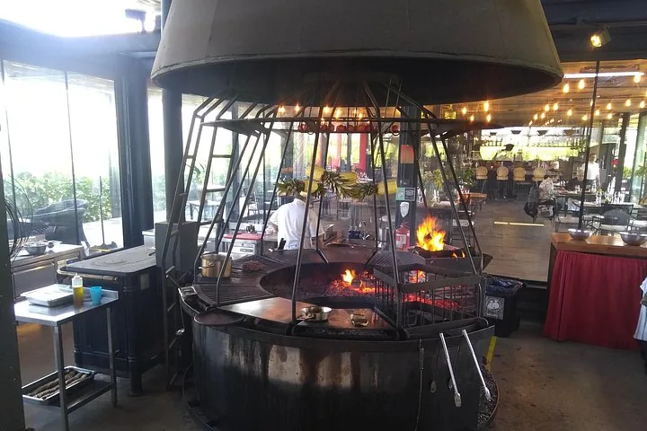 Circular open-fire grill under a large metal dome inside a restaurant