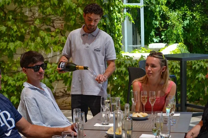 Server in a Viñamar polo pouring sparkling wine for guests on a terrace