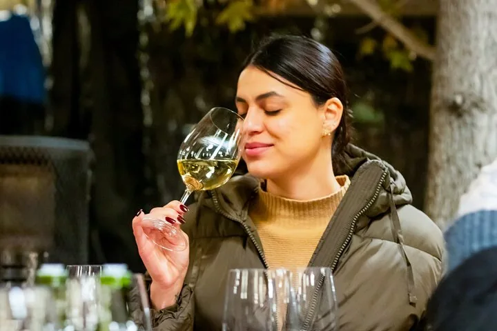 Visitor smelling a glass of white wine at an outdoor table