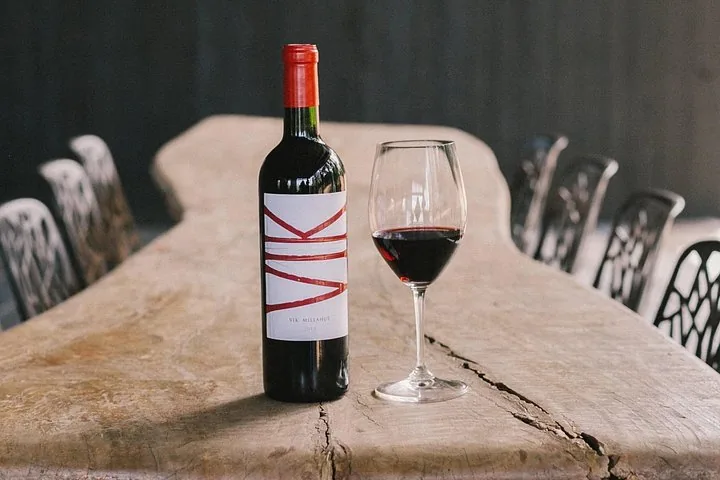 Bottle of VIK Millahue beside a glass of red on a rustic table
